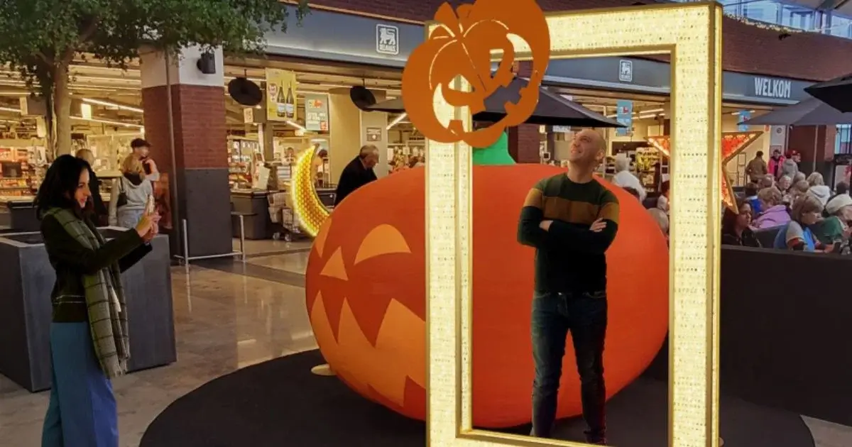 Man posing in light-up frame with pumpkin decoration